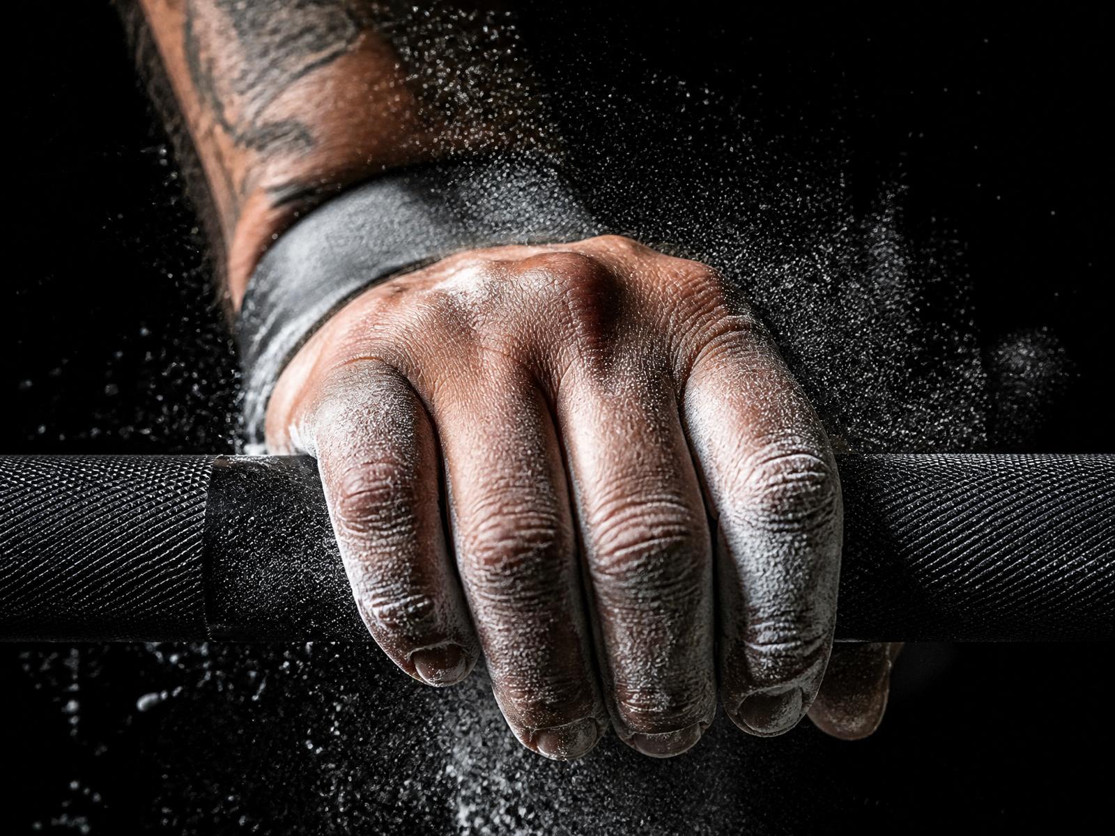 Chalk-dusted hand gripping a knurled barbell